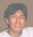A person with short dark hair wears a white shirt against a light brown background, showing two facial expressions in sequence.