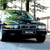 A pixelated image shows a dark vehicle with a greenish upper section and yellow accents, positioned on a light blue surface with blurred background elements.