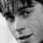 Black-and-white pixelated image of a person's face with visible eyes, nose, and mouth, showing a neutral expression against a light background.