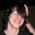 A person with dark hair and glasses smiles while touching their head, with green text reading "Leggo My Greggo!" appearing in the upper right.