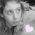 Pixelated grayscale portrait of a person with long hair, wearing dark clothing and holding a light pink heart shape.