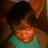 Pixelated image of a person with dark hair wearing a teal shirt against a brown background.