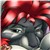 A pixelated image of a dark-furred animal with large eyes and a red hooded garment, set against a blurred background.