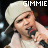 Pixelated image of a person with light-colored hair wearing a white cap, holding a microphone near their mouth against a dark background.