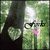 A heart-shaped icon with a green leaf pattern, pink lips, and black glasses against a blurred forest background.