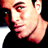 Pixelated close-up of a person's face with visible facial features and partial clothing, rendered in warm tones against a dark background.