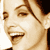 Pixelated close-up of a smiling person's face with visible eyes, nose, mouth, and hair in sepia tones on a white background.