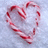 A heart-shaped arrangement of red-and-white striped candy canes on a snowy background, with green pixelated text on a red background reading "Dear Santa All I want for Christmas is... HIM!!!".