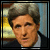 Pixelated portrait of a person with gray hair in a dark suit and light shirt, with yellow text reading 'JOHN' at bottom right in one view and 'KERRY' at bottom left in another.