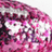 Pixelated image with pink and purple hues forming abstract shapes against a white background, featuring indistinct text-like patterns.