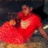 A person in a red shirt with white heart design sits on a bench, legs spread wide apart.