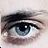 A close-up pixelated image of a human eye with visible eyelashes, eyebrow, and iris details against a light background.