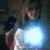 A person in a white top with long hair holds an object emitting bright blue light against a dark background.