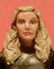 A woman with long blonde hair and a dark top against a solid red background, shown in six of motion