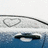 Pixelated static image showing a white vehicle with dark windows on blue water, viewed from above against a light sky.