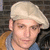 A person wearing a light-colored beret and brown jacket over blue shirt, shown in four with slight head position changes