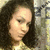 Pixelated close-up of a person with dark curly hair against a blurred background with light and dark tones.
