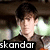 A four- shows a person in dark clothing with text overlays; the bottom displays "completes me <3" while top-left and top-right read "skandar" and "keynes"