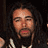 Static 48x48 pixel icon showing a close-up of a person with long dark hair and light skin, wearing a black top with white accents against a dark background.