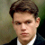 Static 50x50 pixel icon showing a close-up of a person with short brown hair wearing a dark suit jacket and white shirt against a blurred background.