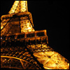 A pixelated nighttime view of the Eiffel Tower's lower section, illuminated with golden lights against a black background.