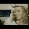 Animated sequence showing a person with long curly hair wearing a light-colored top and cowboy hat, transitioning through various background settings including urban night scenes and water reflections.