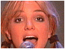 Britney Spears in three : singing into a microphone with mouth open, smiling while holding the mic, and waving one hand