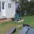 A static image of a house with green grass, trees, and two figures standing near the entrance.