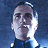 Pixelated static image of a person with short dark hair, light skin, and a neutral expression against a blue background.