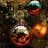 Pixelated static image showing three spherical objects with reflective surfaces against a dark brown background, one partially obscured by text.