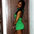 A woman in a green dress stands against a wooden door, her head turning from left to right across frames.