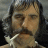 Pixelated portrait of a person with dark hair and a mustache, wearing a light-colored shirt with a white collar, against a muted background.