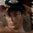 A person wearing a dark cap with white text adjusts the cap while looking downward, captured in an animated sequence.