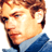 Pixelated close-up of a person with light brown hair wearing a blue collared shirt against a white background.