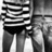 Black-and-white pixelated image of a figure in striped clothing with visible legs and partial torso, set against a gradient background.