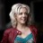 Pixelated image of a person with short white hair wearing a red cardigan over a blue and white top against a dark background.