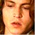 A pixelated close-up of a person's face showing closed eyes, a nose, and lips with visible skin tones and brown hair on the left side.