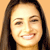 Pixelated close-up of a smiling person with long dark hair against a solid light brown background, rendered in low-resolution 50x50 pixels with visible dithering and color blending.