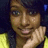 A pixelated close-up of a person with dark hair, light skin, and a yellow garment, holding a hand near their face against a dark background.
