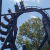 Pixelated static image shows dark metal structure with circular opening and tree silhouette against light blue sky.