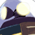 Pixelated static image of a dark purple or black aircraft-like shape with two large circular lights against a light blue background, partially overlapping a brown structure at the bottom right.