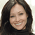 A static pixelated image shows a person with long dark hair wearing a dark top against a light background.