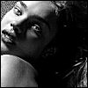 Black-and-white close-up of a person's face with dark hair, showing eyes, nose, mouth, and shoulder in high-contrast monochrome tones.