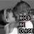 Two identical grayscale figures in profile pose with text overlays reading "HOLD ME CLOSE" and "AND NEVER LET GO".