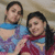 Two women in colorful patterned clothing pose together against a light background, one with long dark hair and the other with shorter dark hair.