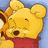 Yellow bear with red shirt and brown nose winking, holding brown object against blue background.