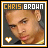 Pixelated portrait of a person with short hair, wearing dark and yellow clothing, under text reading 'CHRIS BROWN' in mixed orange and white lettering.
