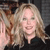 A static pixelated image shows a person with long light brown hair wearing a dark top against a dark background.