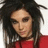 Pixelated close-up of a person with dark curly hair wearing red clothing against a light background.