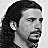 A grayscale portrait of a man with long dark hair and a goatee, shown in multiple positions with green heart symbols appearing sequentially